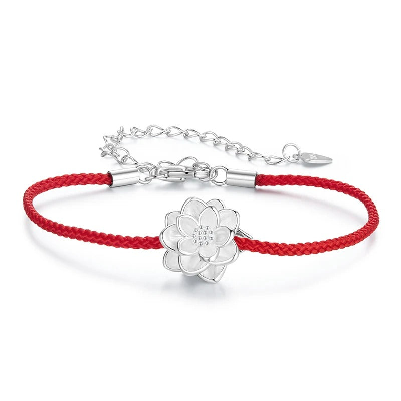 Silver bracelet with a flower charm on a red cord against a white background